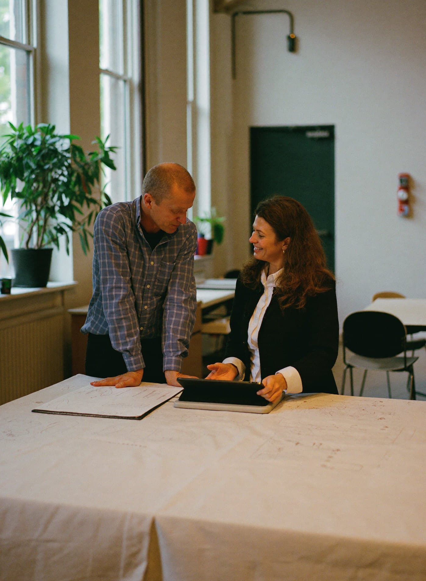 Twee collega's bespreken samen een tekst op een tablet aan een werktafel